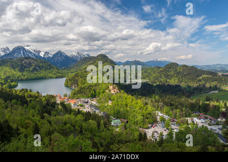 Vista sul castello di Hohenschwangau in Germania da oriente con il lago Alpsee e alpi e cielo blu con nuvole in background. Foto Stock