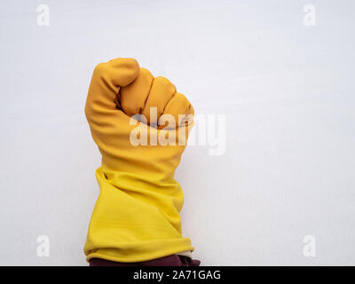 Mani che indossa giallo brillante guanti di gomma su un panno bianco sullo sfondo Foto Stock