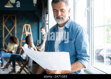 Sorridente società invecchiata boss in posa di office Foto Stock