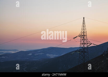 Bella vista dalla cima della montagna durante il tramonto con fili di elettricità nella parte anteriore che simboleggiano la presenza umana nella natura Foto Stock