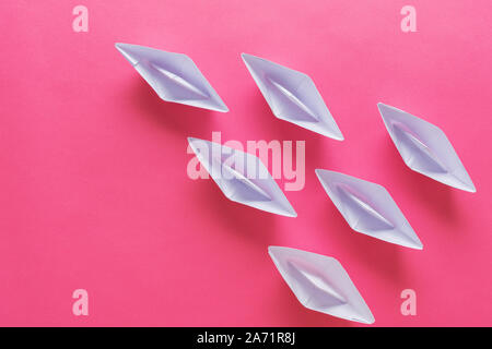 Sei carta origami realizzato barche su sfondo rosa in una immagine concettuale. Con copia spazio. Foto Stock