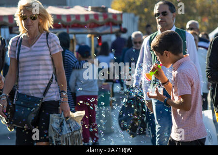 Istanbul, Turchia - Settembre-28,2019: bambino bolla di vendita della macchina su strada e un po' di bolle di sapone intorno a. Sfumata la gente camminare nel backgro Foto Stock