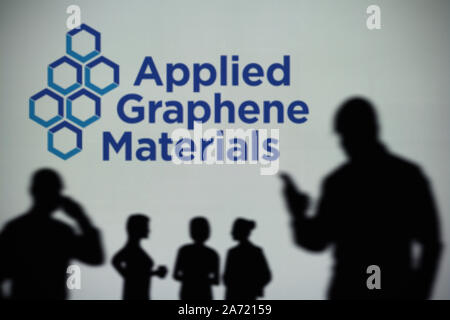 L'applicazione di materiali grafene logo è visibile su uno schermo a LED in background mentre si profila una persona utilizza uno smartphone (solo uso editoriale) Foto Stock