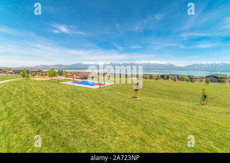 Parco e alloggia in corrispondenza di una zona residenziale con vista di Snow capped mountain e il lago Foto Stock