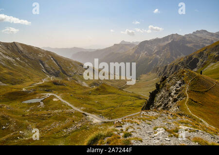 Vista in elevazione del Colle dell'Agnello mountain pass con la strada tortuosa e il Lago di Pic d'Asti in tarda estate, Chianale, Cuneo, Piemonte, Italia Foto Stock