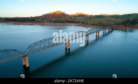 La bassa altitudine antenna della Bethanga ponte che attraversa il fiume Murray. Inizio morninglight con la prima luce del sole di colpire le colline in background. Foto Stock