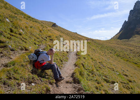 Esaurito l uomo sta prendendo una pausa durante un tour escursioni nelle montagne Rofan, Austria Foto Stock