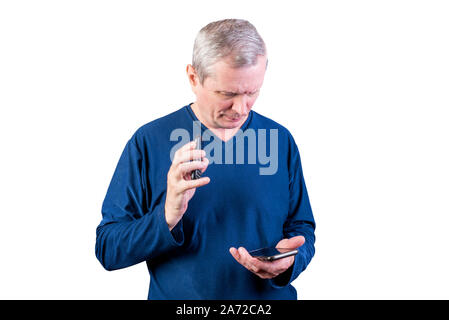 Un anziano uomo sceglie tra un vecchio telefono e uno smartphone. Isolato su uno sfondo bianco. Foto Stock