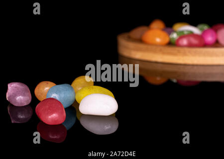 Sacco di tutta jelly bean caramella sul bambù rotondo coaster isolato sul vetro nero Foto Stock