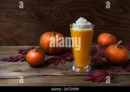 Rientrano in casa vegan pumpkin spice latte con panna montata su tavola in legno rustico Foto Stock