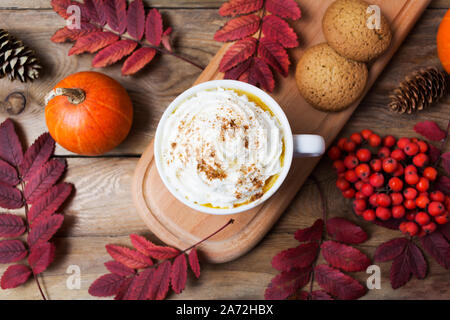 La zucca spice caffè latte mug con panna montata, cookie, cadono le foglie e bacche di rowan, vista dall'alto Foto Stock