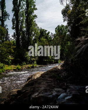 Piccolo fiume che scorre in un piccolo borgo rurale con alberi di grandi dimensioni e formati in modo univoco le rocce, forni fiume Bright Victoria Australia Foto Stock