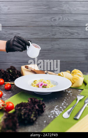 Spaghetti con olio di oliva arricchito di colori con il verde, mattarello, pasta. Square. Foto Stock