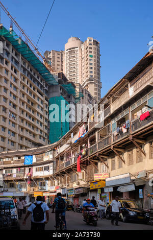 Khadilkar strada in area Bhuleshwar, Mumbai, India, con tradizionali vecchie case nella parte anteriore e i nuovi edifici di appartamenti che torreggia sullo sfondo Foto Stock