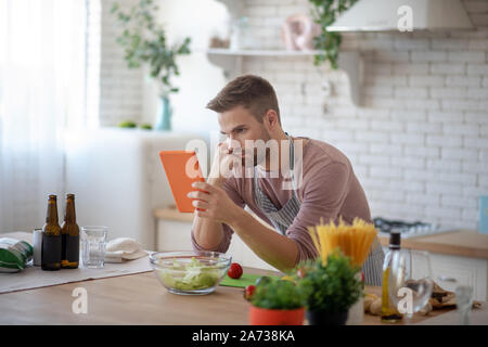 Barbuto marito guardando video culinario su tablet Foto Stock