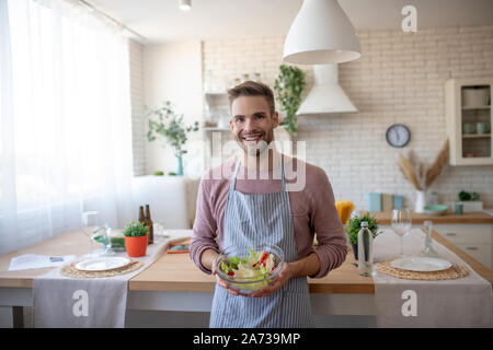 Uomo con ciotola con insalata in piedi vicino a tabella Foto Stock