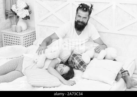 La fine della serata pazzo. Avendo divertimento pigiama party. Slumber party. Felice della paternità. Papà e una ragazza rilassante camera da letto. Pigiami stile. Padre uomo barbuto divertente ponytails di acconciatura e la figlia in pigiama. Foto Stock