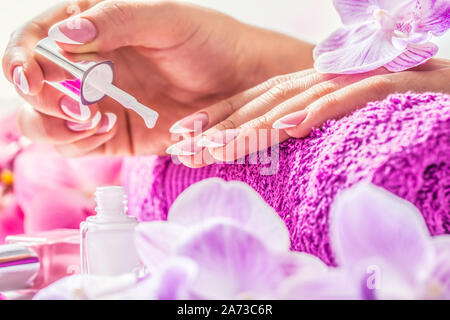 Mani femminili bianco applicazione smalto per unghie nel salone di bellezza Foto Stock