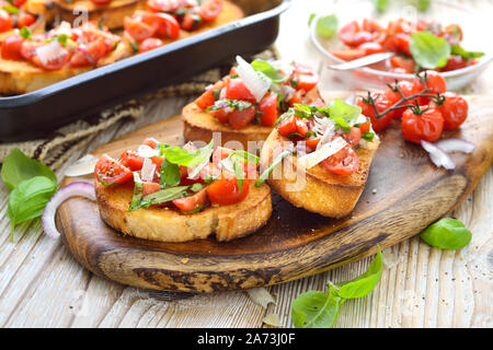 Calda bruschetta italiana: croccante italiano cotto ciabatta Pane con pomodori ciliegia, basilico e parmigiano e servita come antipasto Foto Stock