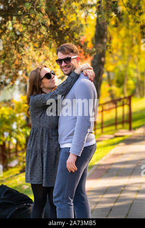 Sorridenti amorevole coppia giovane abbracciando in un parco d'autunno con colorati fogliame stagionale Foto Stock