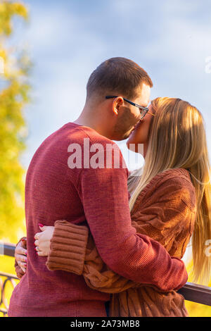 Affettuosa giovane baciare la sua ragazza sulla guancia come stanno in un abbraccio all aperto in autunno Foto Stock