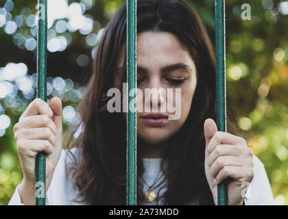 Triste donna dietro le sbarre Foto Stock