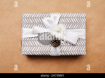 Close-up del bellissimo regalo di natale Scatola decorata con nastro bianco su sfondo marrone Foto Stock