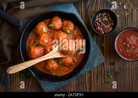 In casa le polpette di carne con salsa di pomodoro e prezzemolo su legno Foto Stock