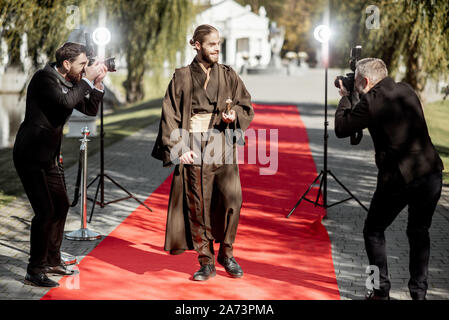 Uomo in costume come un ben noto personaggio del film a piedi con fastidiose foto Reporters sul tappeto rosso durante la cerimonia di premiazione Foto Stock