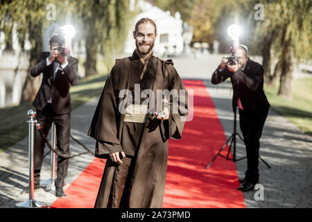 Uomo in costume come un ben noto personaggio del film a piedi con fastidiose foto Reporters sul tappeto rosso durante la cerimonia di premiazione Foto Stock