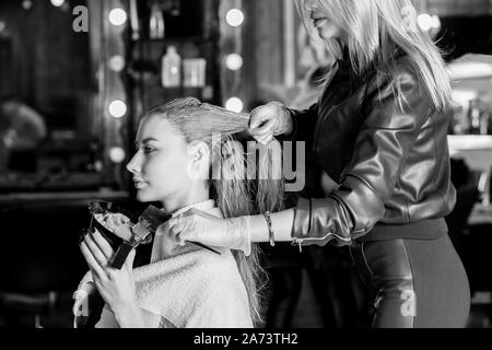 Raddrizzatura di cheratina, la levigatura, la colorazione dei capelli e trattamento. Femmina professionale estetista applicato la maschera a femmina cliente al salone di bellezza. Capelli Foto Stock