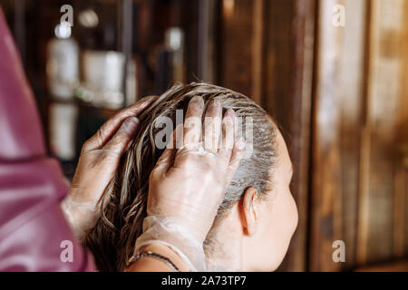 Raddrizzatura di cheratina, la levigatura, la colorazione dei capelli e trattamento. Femmina professionale estetista applicato la maschera a femmina cliente al salone di bellezza. Capelli Foto Stock