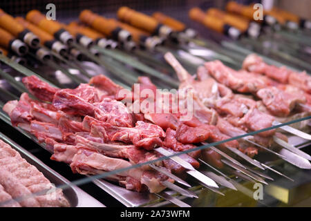 Semilavorati di prodotti a base di carne su spiedini in magazzini frigorifero. Bistecche di carne, nervature pronti per la tostatura su incendio. Concetto di ristorazione. Foto Stock