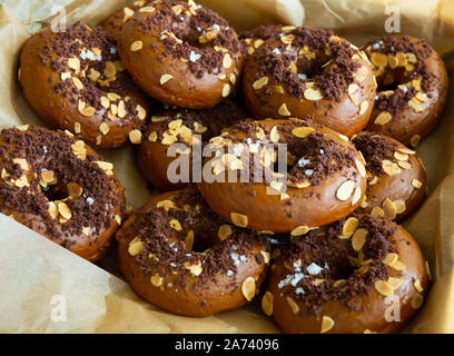 Scatola con appena fatti ciambelle colorate sul display in una pasticceria Foto Stock