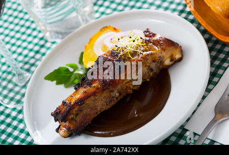 Appetitosa carne di maiale arrostito nervature in delicata salsa al cioccolato con verdura guarnite di patate al forno, cipolla e verdi Foto Stock