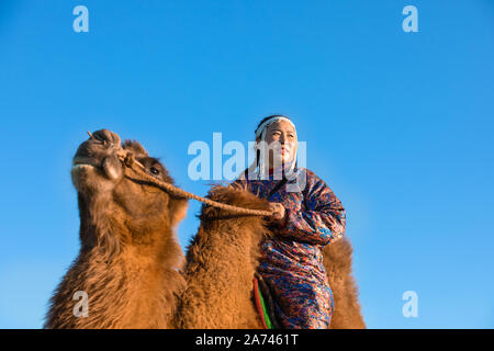 La donna nel tradizionale abito mongolo con il suo cammello bactrian. Deserto dei Gobi, Mongolia. Foto Stock
