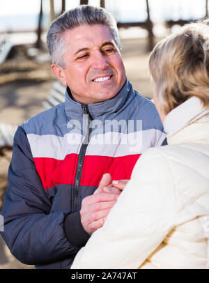 Sorridente Coppia matura tenendo le mani ogni altro sulla giornata di sole nel parco Foto Stock