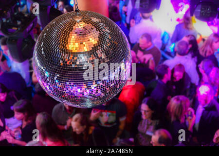 Palla da discoteca con persone non identificabili in background all'interno di una discoteca. Foto Stock