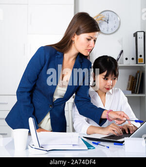 Ritratto di due imprenditrici di successo con sicurezza lavorando sul computer portatile in ufficio moderno Foto Stock
