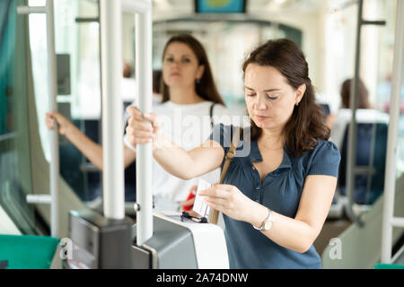 Giovane donna biglietto di inserimento in una moderna macchina punzonatrice, la convalida del biglietto di trasporto pubblico Foto Stock