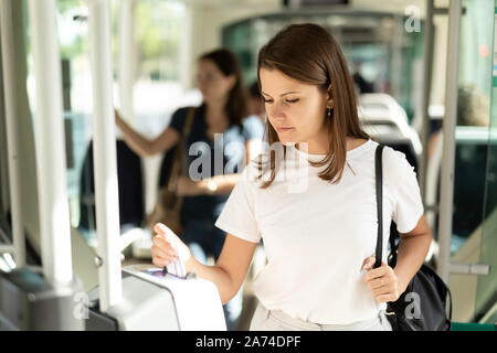 Giovane donna biglietto di inserimento in una moderna macchina punzonatrice, la convalida del biglietto di trasporto pubblico Foto Stock