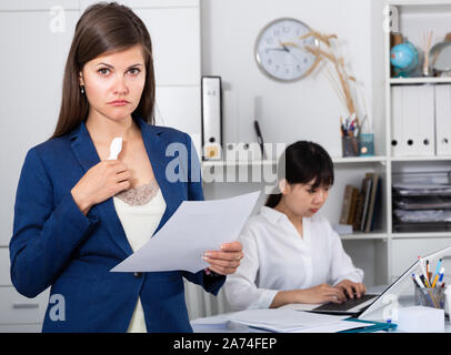 Ritratto di donna ricalcato tenendo la lettera di licenziamento in piedi in ufficio, donna asiatica lavorando sullo sfondo Foto Stock