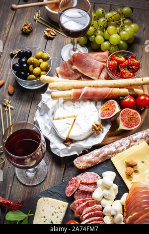 Antipasti all'italiana con prosciutto, prosciutto, formaggio, olive e grissini grissini rustico sfondo di legno Foto Stock