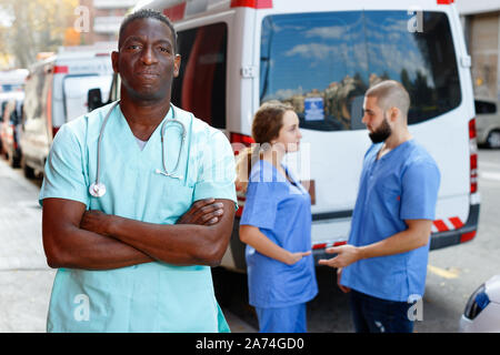 Ritratto di positivo efficiente ambulanza amichevole personale paramedico in piedi vicino a ambulanza Foto Stock