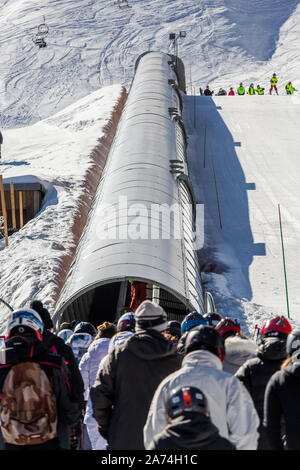 La Mongie, Francia - 21 Marzo 2019:vista posteriore della folla di persone in un caldo abbigliamento esterno in piedi vicino a struttura tubolare sul pendio della montagna innevata sul reso di sci Foto Stock