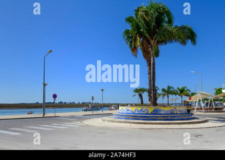 Palme sul lungomare e passeggiata a Santa Luzia contro la Ria Formosa. Santa Luzia Algarve, Portogallo. Foto Stock