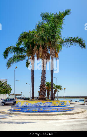 Palme sul lungomare e passeggiata a Santa Luzia contro la Ria Formosa. Santa Luzia Algarve, Portogallo. Foto Stock