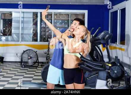 Sorridendo felice coppia atletico rendendo selfie durante la pausa nella sessione di allenamento in palestra Foto Stock