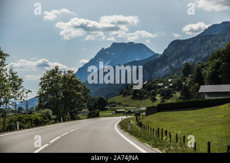 Autobahn o autostrada con un ponte in montagna con marcatura chiara circondato da vivaci alberi verde sotto il cielo blu. Foto Stock