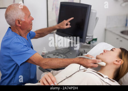 Uomo anziano ecografista mediante ultrasonografia macchina controllo paziente femmina in ospedale camera diagnostica Foto Stock